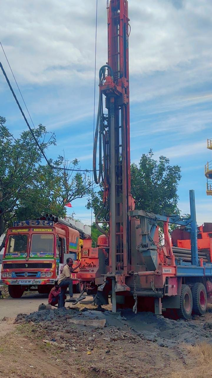 Drill mast raised with crew and support truck alongside
